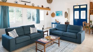 Sala de estar com dois sofás azuis, uma mesa de centro de madeira e uma porta azul.