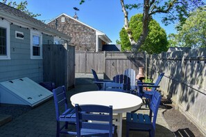 A backyard with a wooden fence, a table with chairs, and a small garden area.