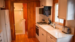 Une cuisine de taille réduite, dotée de meubles en bois, d’un four encastré, d’une cuisinière et d’un évier.