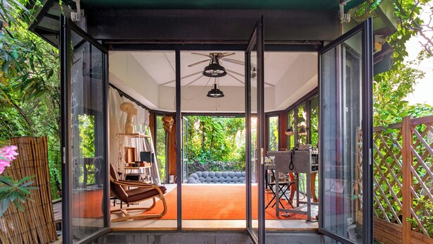 A modern glass-enclosed room with a ceiling fan, a sofa, and a desk with a lamp. - Elegant villa with a park, large private pool, outdoor games, and fitness facilities (verona)