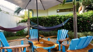 Un espace patio avec des chaises bleues et en bois, une table en bois et un hamac.