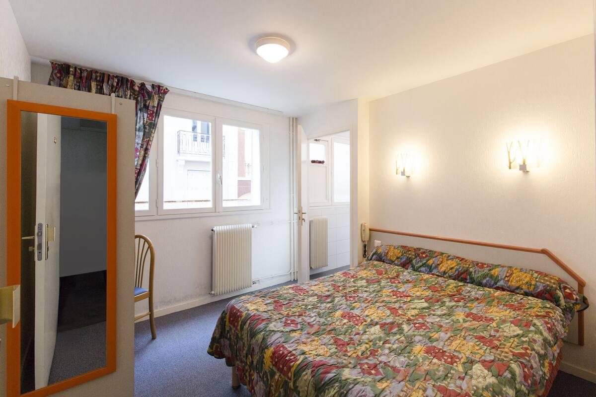 A bedroom with a bed, a chair, a window, and a door.