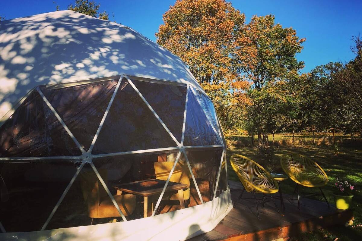 A geodesic dome structure with a wooden deck and outdoor seating.