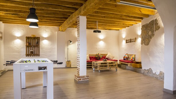 Una habitación con mesa de fútbol, sofá y techo de madera.