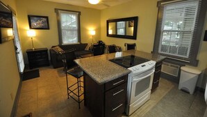 A compact kitchen with a central island, a stove, and a refrigerator. There are two chairs and a dining table.