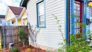 A house with a blue door, a small garden with mulch, and a wooden fence.