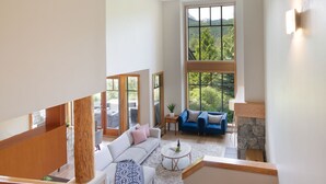 Ein geräumiger Wohnbereich mit großem Fenster, einem Steinkamin und einem blauen Sofa.