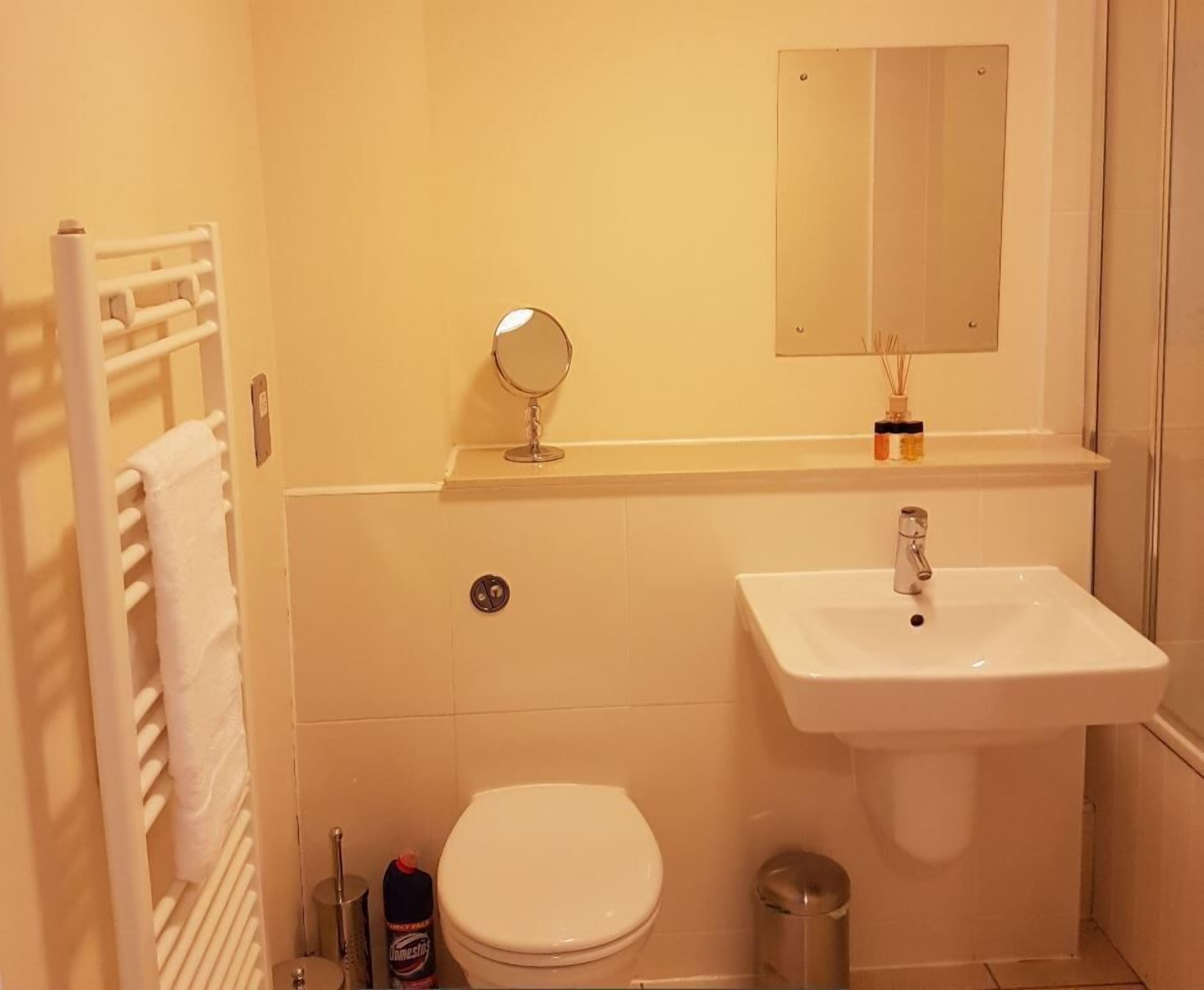 Un baño pequeño con un lavamanos blanco, un inodoro, un espejo y un perchero para toallas.