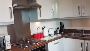 Eine moderne Küche mit Edelstahlgeräten, weißen Schränken und einer Holz Arbeitsplatte.