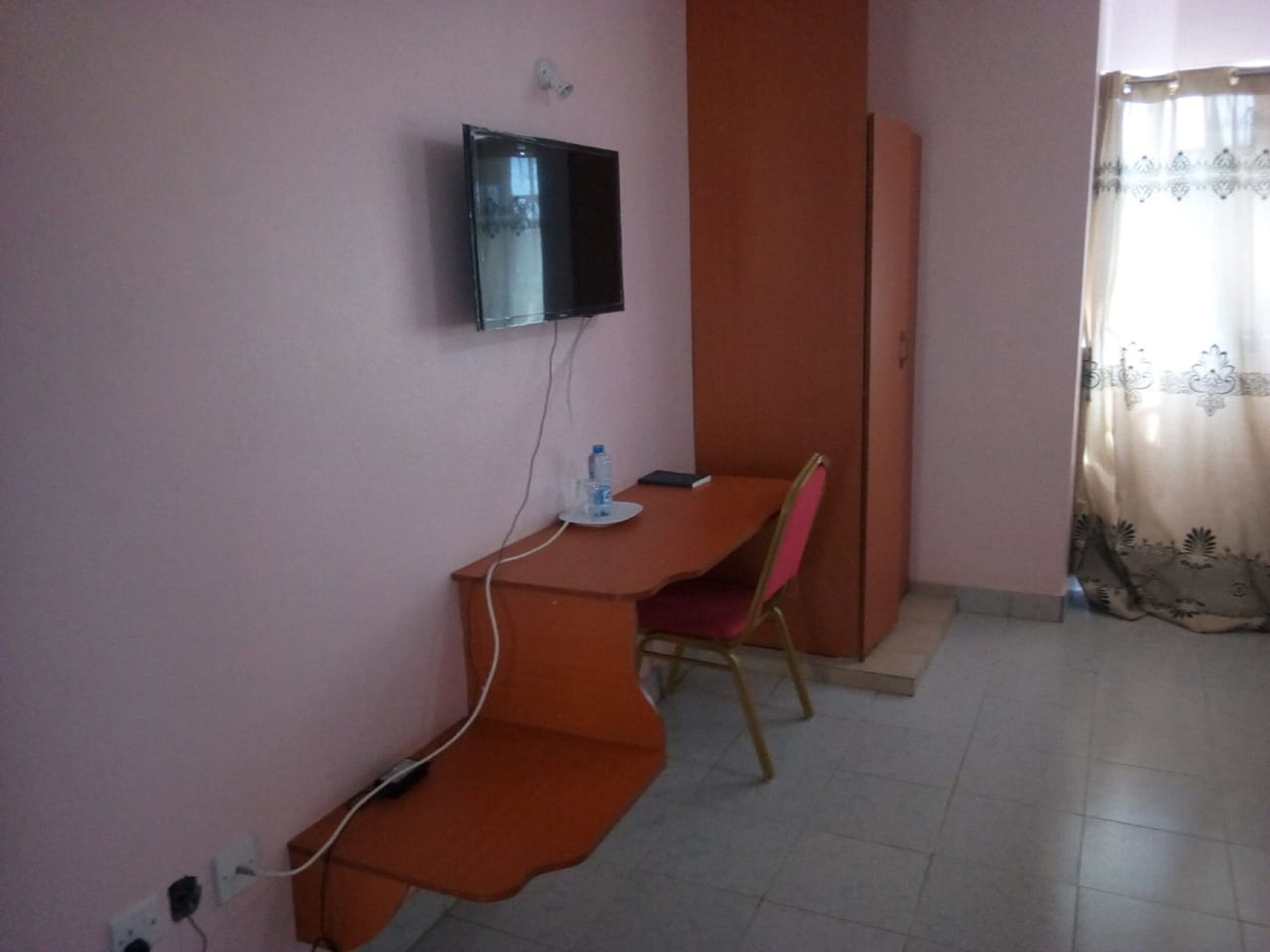 Una habitación pequeña con escritorio, silla y televisor montado en la pared.
