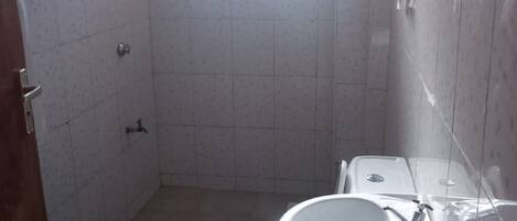 A small, tiled bathroom with a toilet, sink, and a window allowing natural light.