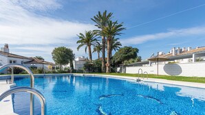 A swimming pool with clear blue water, metal pool ladders, and palm trees in the background. - Genteel Home La Casita (Estepona)