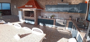An outdoor kitchen with a brick wall, a grill, and a sink.