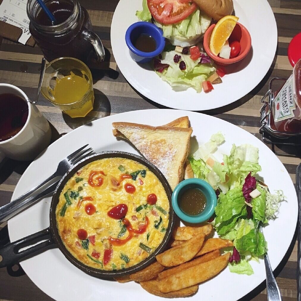 Un plato de desayuno con tostadas, ensalada, patatas fritas y una tortilla en sartén.