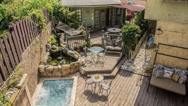 A backyard with a hot tub, a wooden deck, outdoor seating, and a fenced area. - One32 Guest House (Kingston)