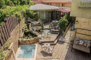 A backyard with a hot tub, a wooden deck, outdoor seating, and a fenced area. - One32 Guest House (Kingston)