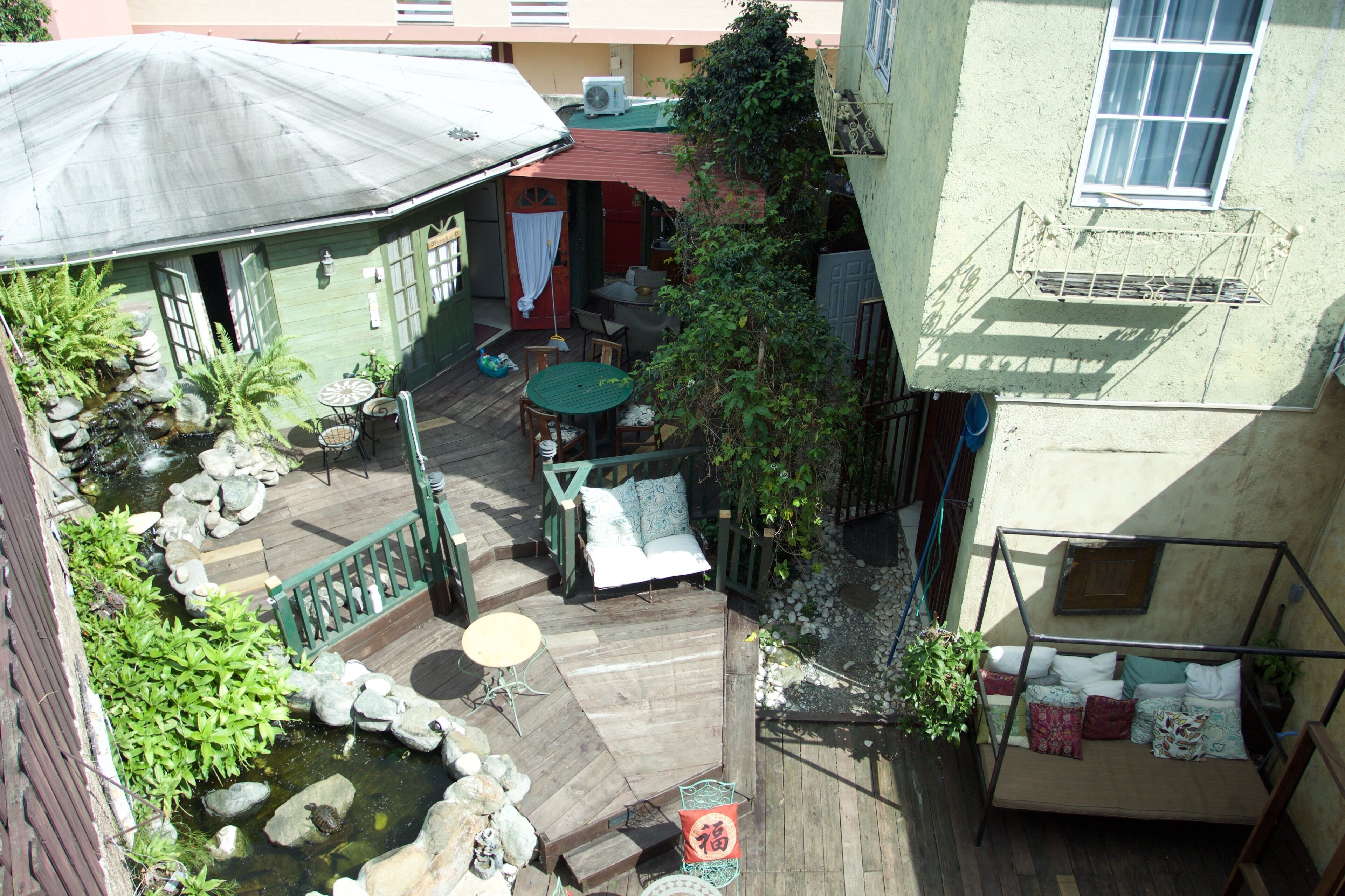 Un patio con una terraza de madera, un pequeño estanque y una zona de estar con una mesa y sillas.