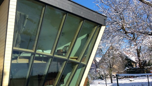 A modern building with large glass windows and a slanted roof. - Single gîte heliodome (Ostwald)