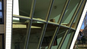A modern building with large floor-to-ceiling windows, a brick exterior, and a visible interior with furniture. - Single gîte heliodome (Ostwald)