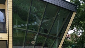 A modern building with large glass windows, a well-maintained garden with stepping stones, and outdoor furniture. - Single gîte heliodome (Ostwald)