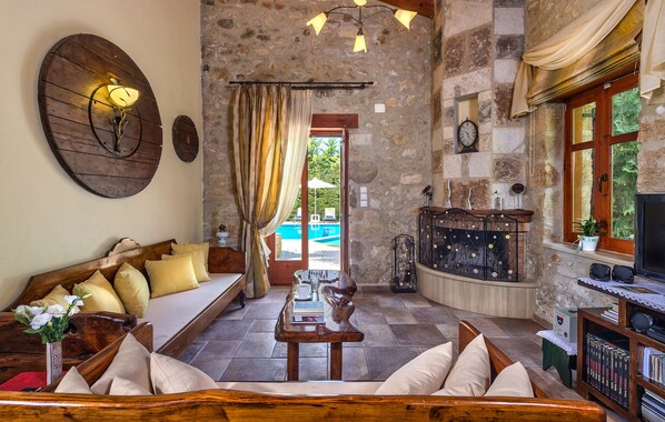 A cozy living room with a wooden sofa, a coffee table, and a stone wall.