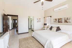 A bedroom with a large bed, a ceiling fan, an air conditioning unit, and artwork on the wall. - Bella Constantina Villa In Anguilla. Modern Design With Breath-Taking View (Elsie Bay)