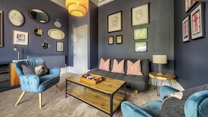 Una sala de estar moderna con un sillón azul, un sofá gris y una mesa de centro de madera.