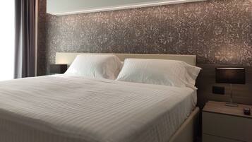A neatly made bed with white linens, a headboard, and two bedside lamps on a nightstand.