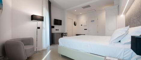 Een moderne hotelkamer met een groot bed, een bureau met stoel, een staande lamp en een flatscreen televisie.