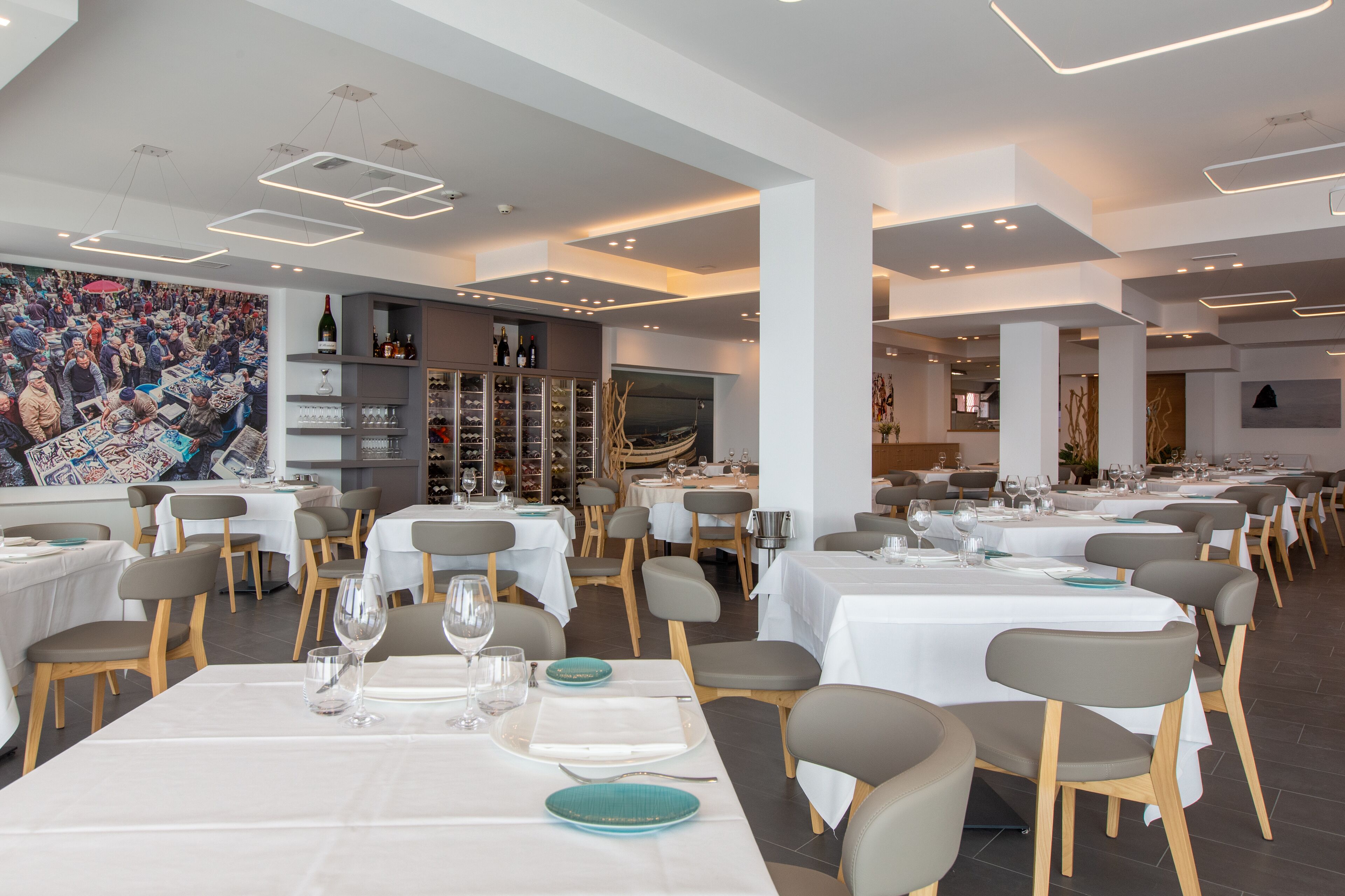 A spacious restaurant with multiple dining tables, chairs, and a wine rack.