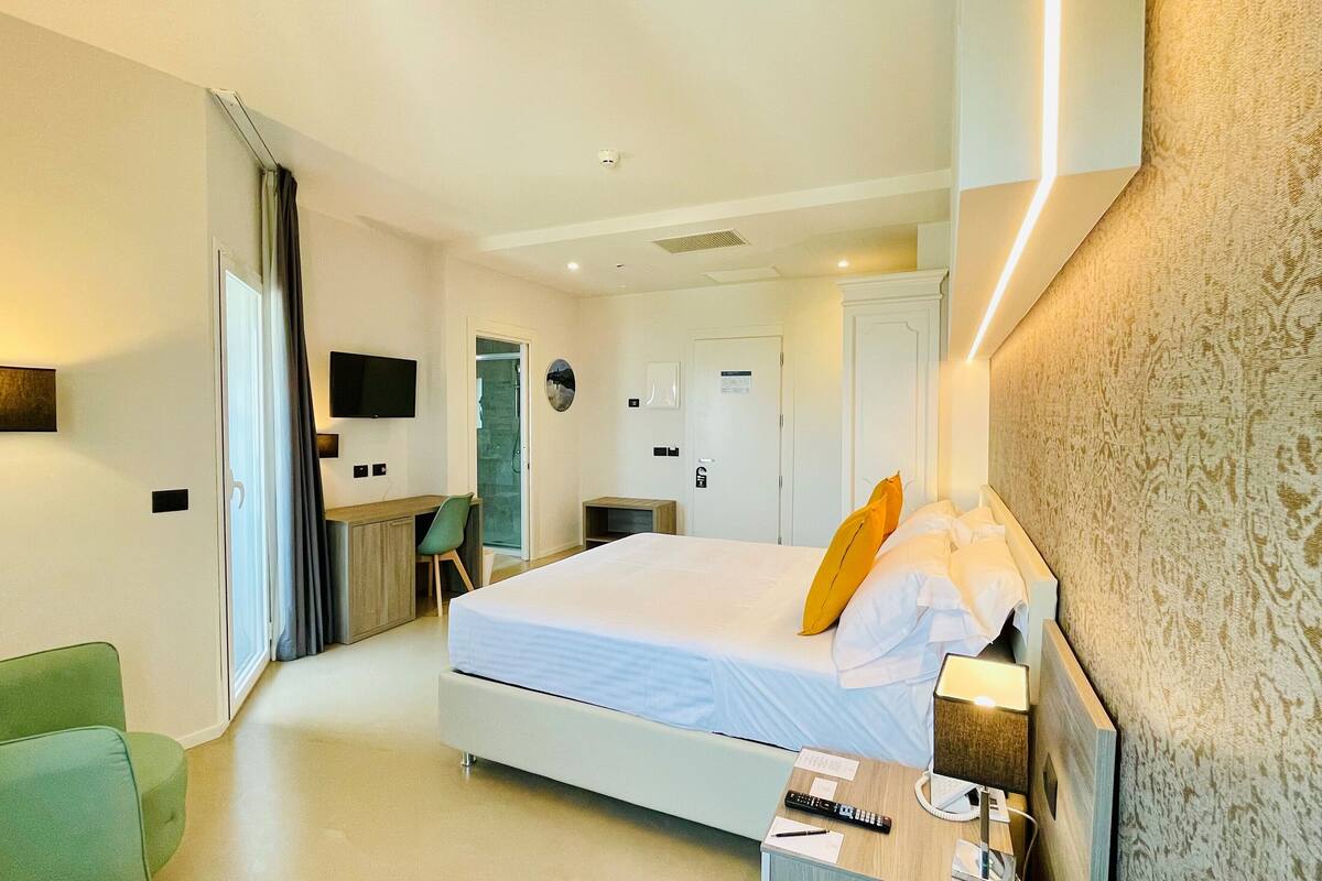 Een hotelkamer met een bed, een bureau, een stoel, een televisie en een badkamer.