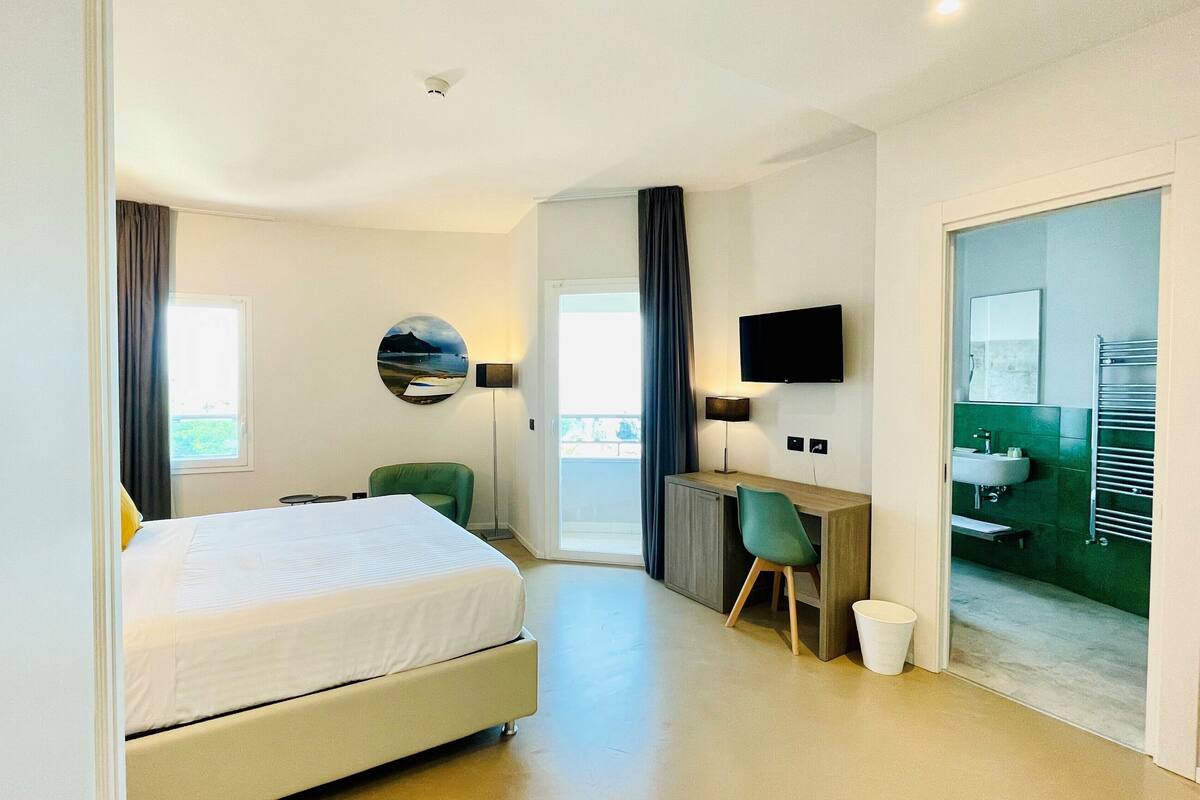 Een moderne hotelkamer met een bed, bureau en zithoek.