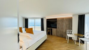 Una habitación de hotel moderna con una cama grande, un televisor, un escritorio y una silla.