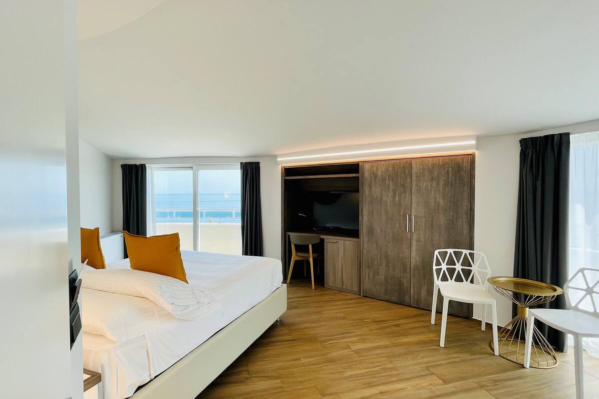 Een moderne hotelkamer met een groot bed, een televisie, een bureau en een stoel.