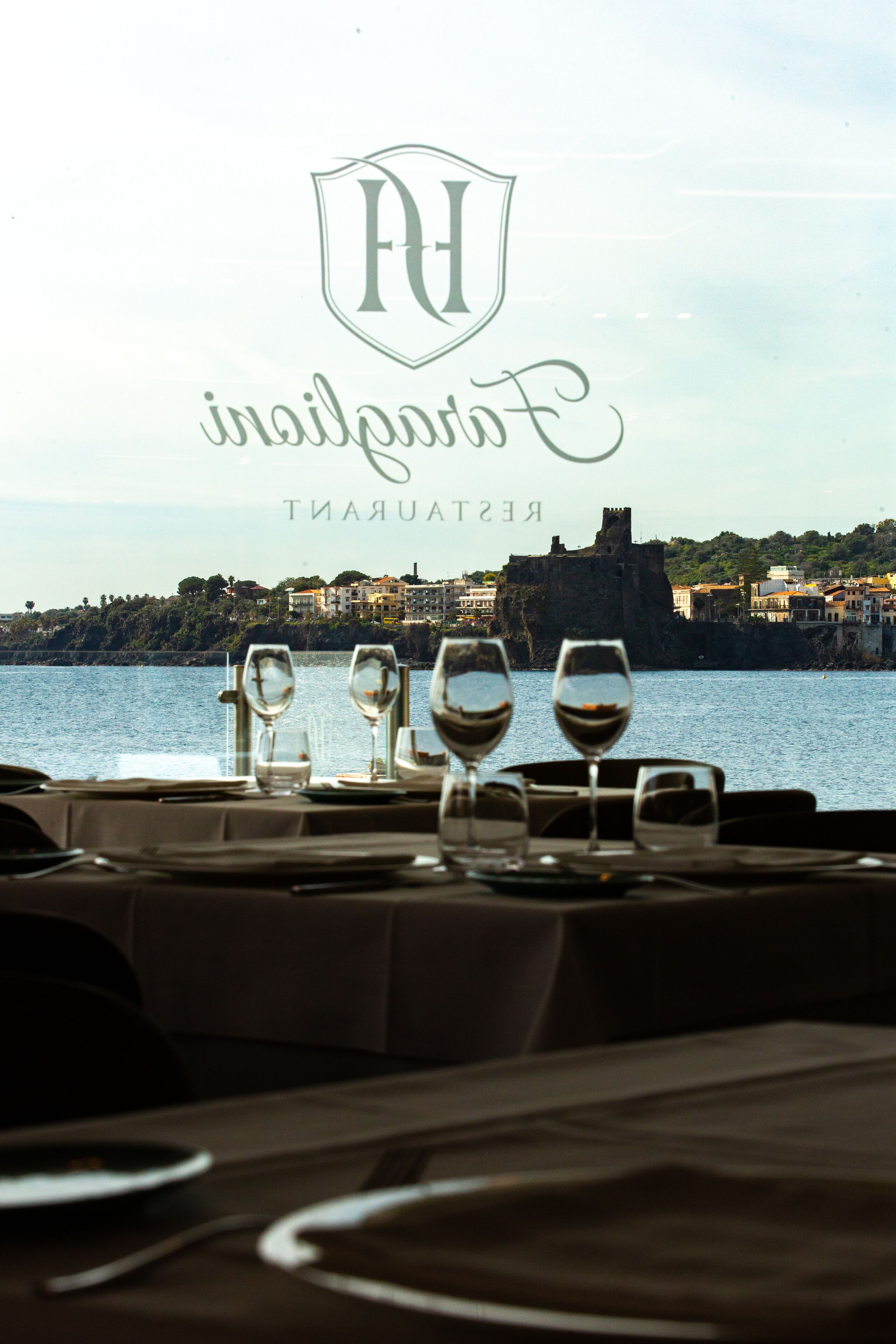 Mesa lista para comer con vistas a un pueblo costero y un castillo al fondo.