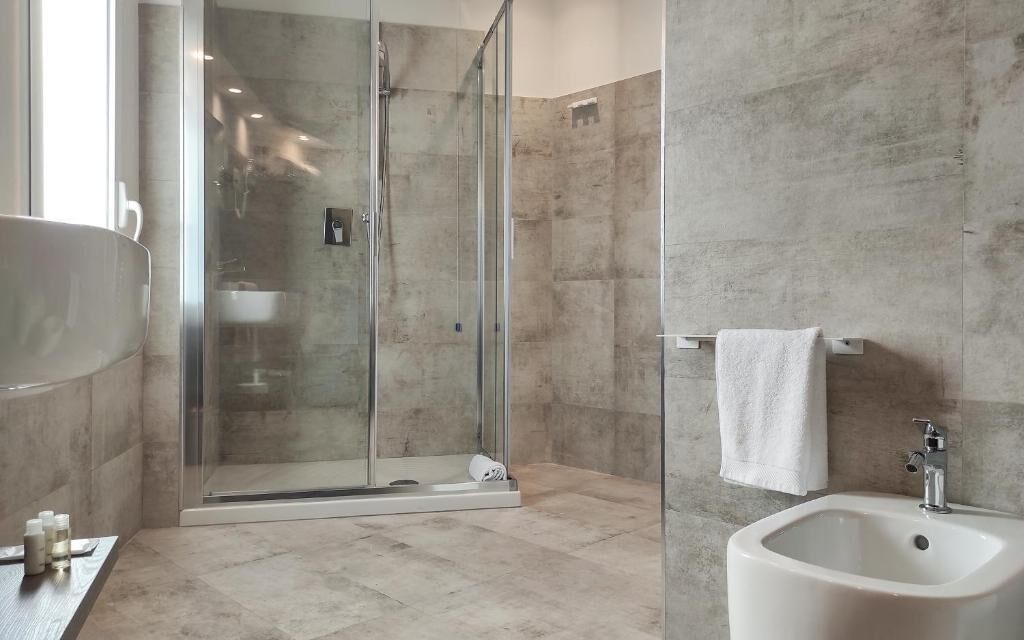 A modern bathroom with a glass-enclosed shower, a sink, and a bidet.