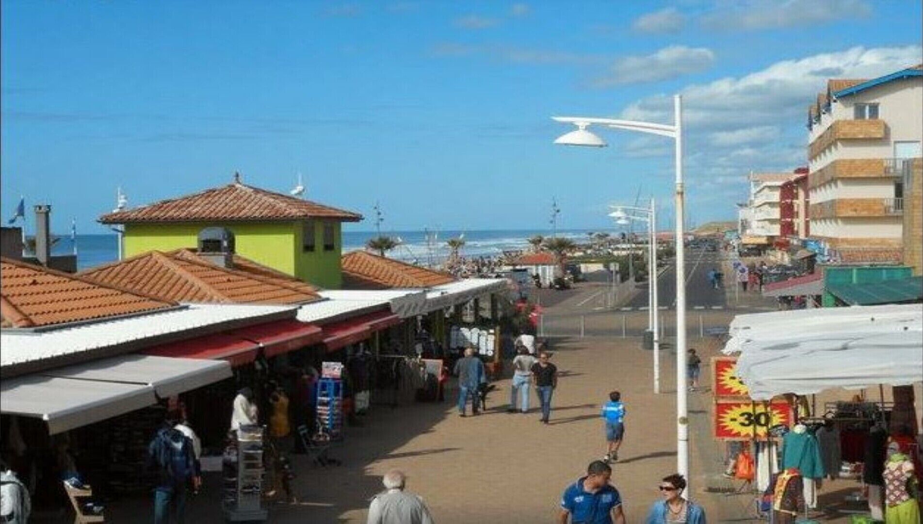 A coastal street with shops and a beach in the background.
