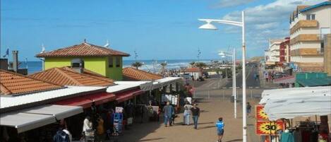 A coastal street with shops and a beach in the background.