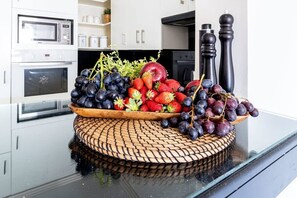 A kitchen counter with a fruit display including grapes, strawberries, and an apple.