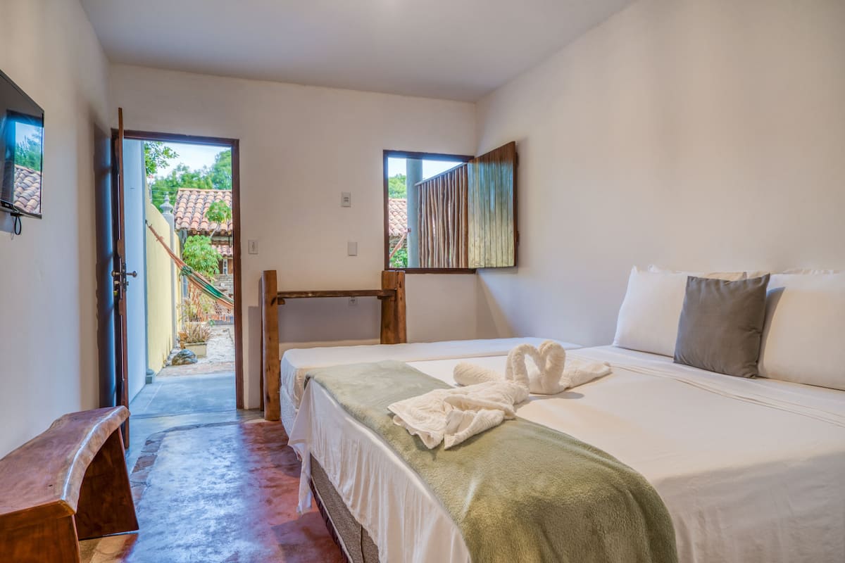 Un dormitorio con cama, una banca, una ventana y vista a un patio.
