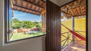 A room with a large window, a wooden door, and a hammock. - Pousada Trilha do Mar (Marechal Deodoro)