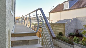 Un escalier avec des rampes en métal menant à une terrasse en bois.