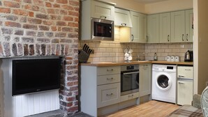 Une cuisine compacte avec un mur en briques, un four à micro-ondes, un lave-linge et un lave-vaisselle.