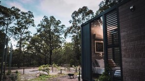 Una casa moderna amb una porta de vidre que dona a un dormitori amb un llit i una finestra.