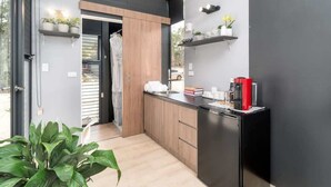 Una cuina moderna amb armaris de fusta, un refrigerador negre i plantes en testos.