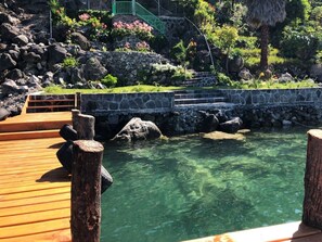 A clear pool with wooden deck and stone steps leading into it, surrounded by greenery and rocks. - CasaDePiedra, CerroDeOro, LagoAtitlan, Brand New (Sector Tzanguacal)