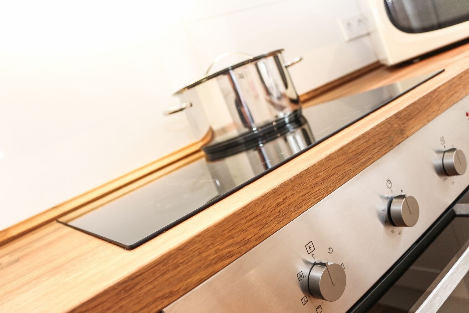 Una cocina con encimera de madera, estufa de acero inoxidable y una olla sobre la hornilla.