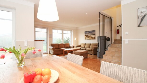 Un salón espacioso con una mesa de comedor de madera, dos sofás y una escalera que lleva a un piso superior.