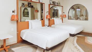 A hotel room with two beds, a large mirror, a small table, and a decorative rug.