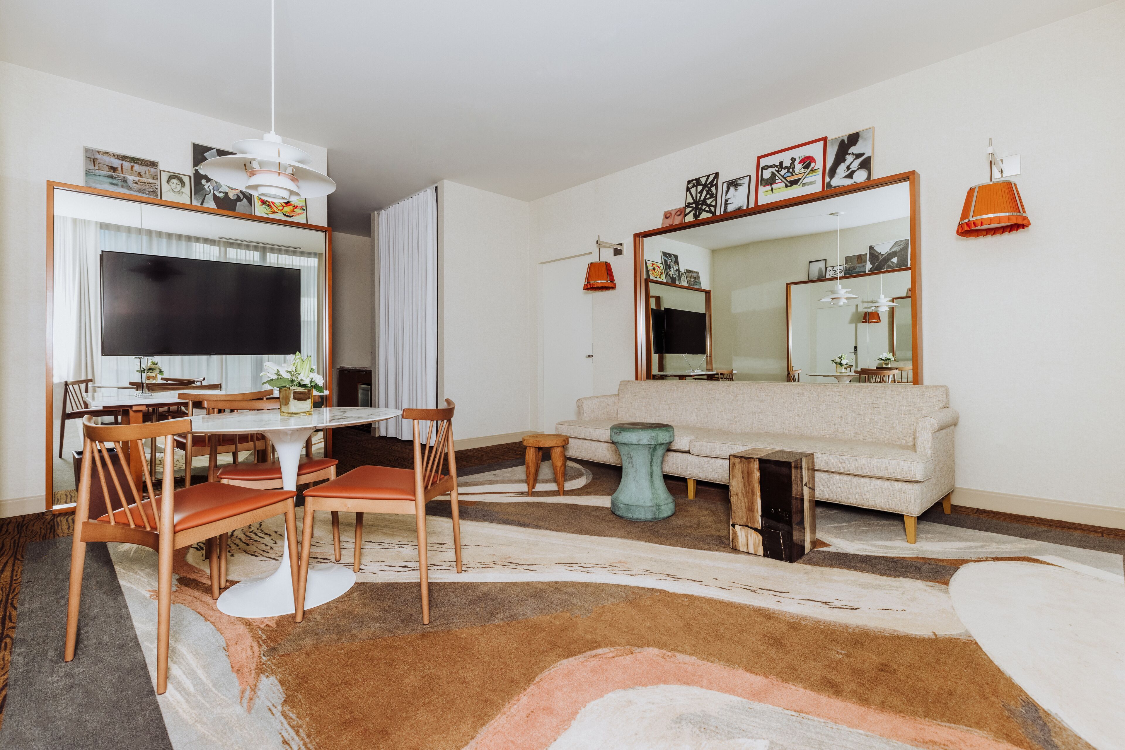 A modern living room with a dining area, a large flat-screen TV, a sofa, and a coffee table.